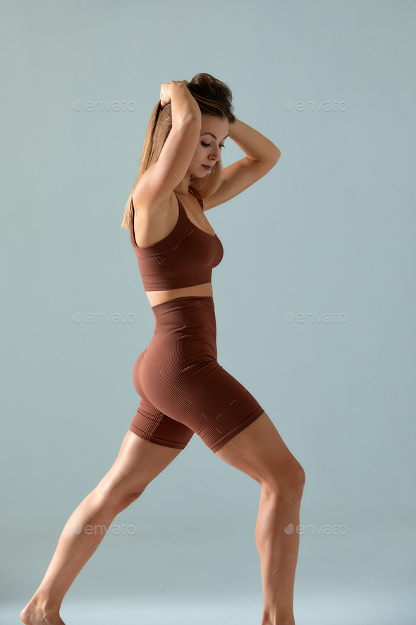 Portrait of young fit and sportive woman on gray background. Fit