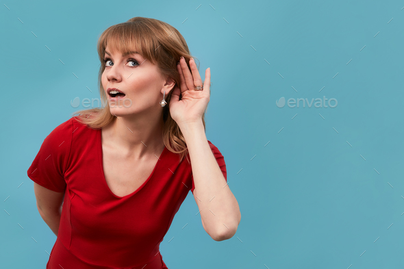 Portrait of an attrative long hair young woman making what did you say sign by putting her hand to