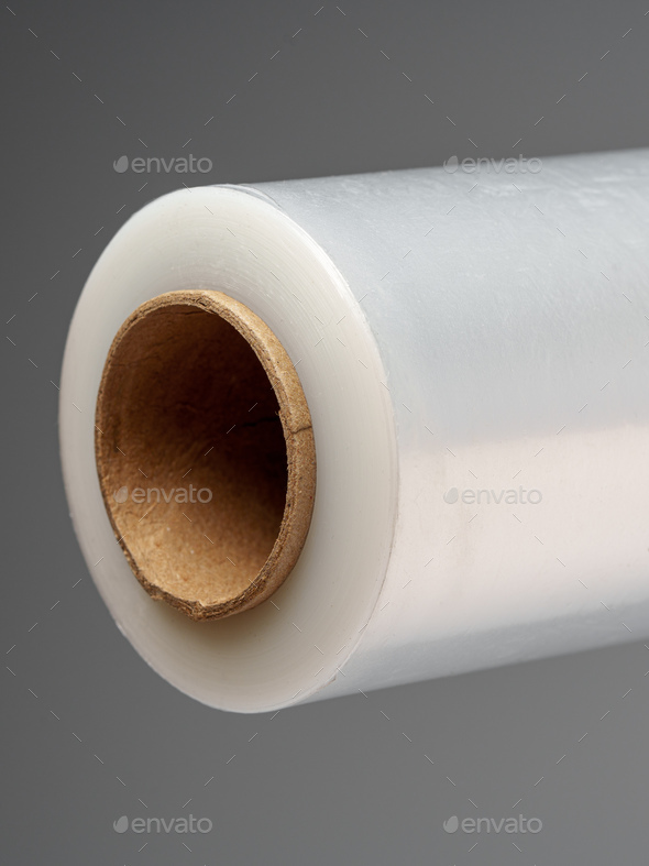 Roll of transparent polyethylene cling film on gray background