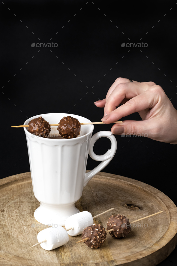 A woman's hand stirs hot chocolate with chocolates skewer - Stock Photo - Images