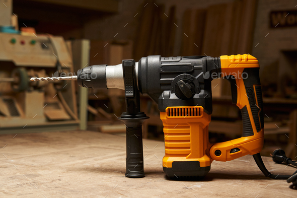 side view of a modern electric rotary hammer with vertical motor, mounted drill and additional