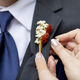Detail shot of hands pinning on a boutonnniere on a grooms suit - PhotoDune Item for Sale