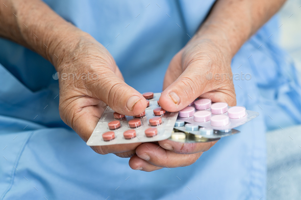 Asian elderly woman patient holding drug in her hand, healthy strong medical concept. - Stock Photo - Images