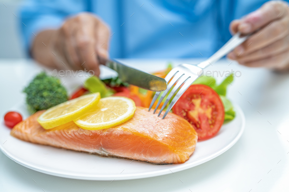 Asian elderly woman patient eating salmon steak breakfast with vegetable healthy food in hospital. - Stock Photo - Images