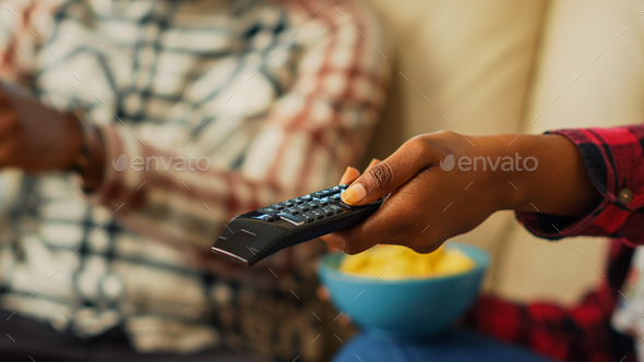Young girlfriend using tv remote control to watch film