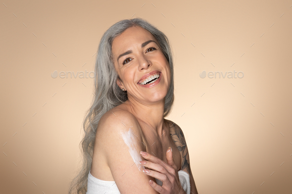 Woman Wrapped with Bath Towels, Applying Cream on her Face Stock