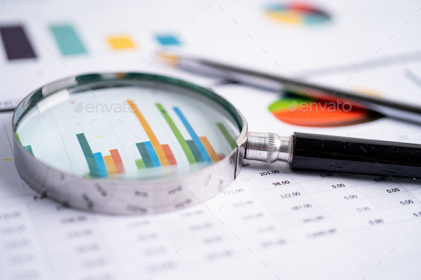 Magnifying glass on charts graphs paper.  - Stock Photo - Images