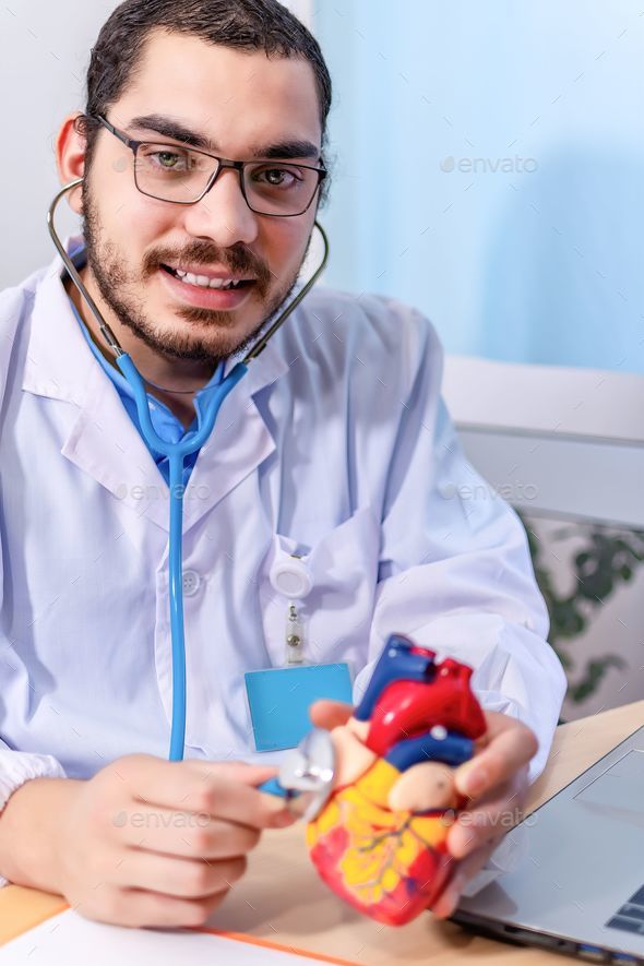 Vertical shot of a Cardiologist with a stethoscope touching a heart anatomical model
