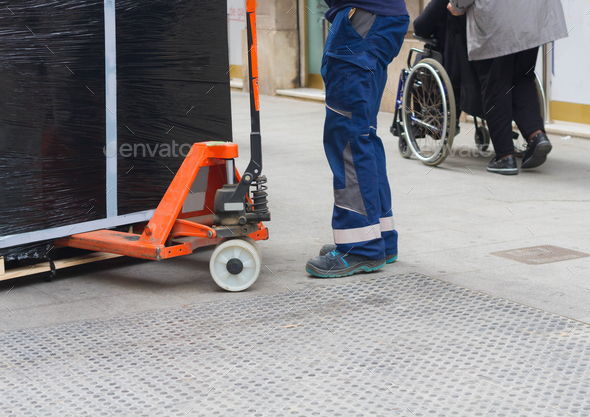 Worker With Fork Pallet Truck Stacker In Warehouse Loading Furniture