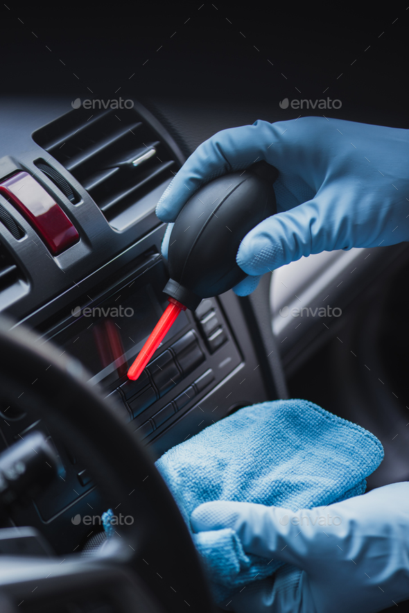 cropped view of car cleaner dusting dashboard with rubber air cleaner