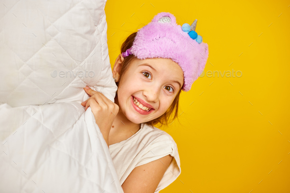 Funny teenage girl in white pyjamas with a violet sleeping mask hold pillow - Stock Photo - Images