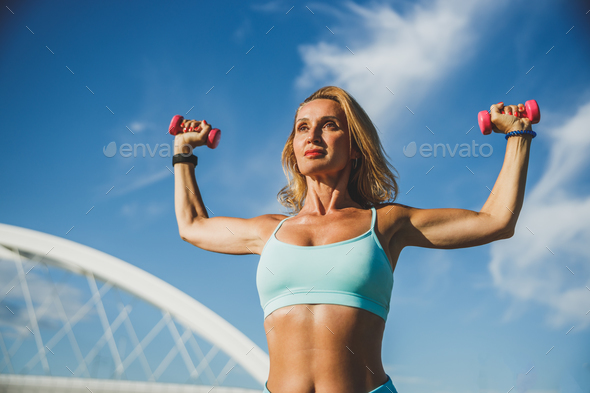 Fit Woman Using Hands Weights While Doing Outdoors Workout