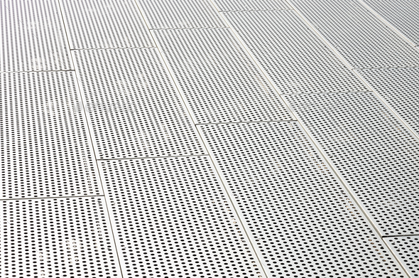 Diagonal view of metall grilles and round holes in metal surface, perforated panels
