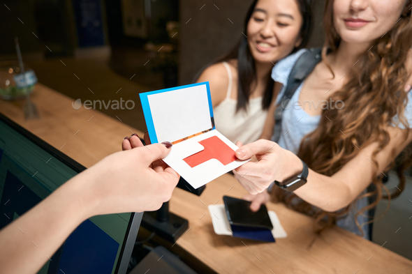 Cropped photo of happy women receiving room key at reception