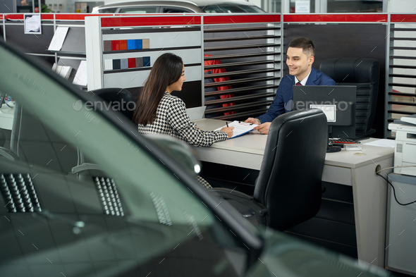 Young asian woman and car dealership manager communicate in office area
