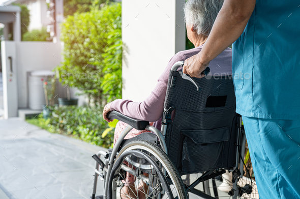 Caregiver help and care Asian senior woman patient sitting in wheelchair on ramp at hospital. - Stock Photo - Images