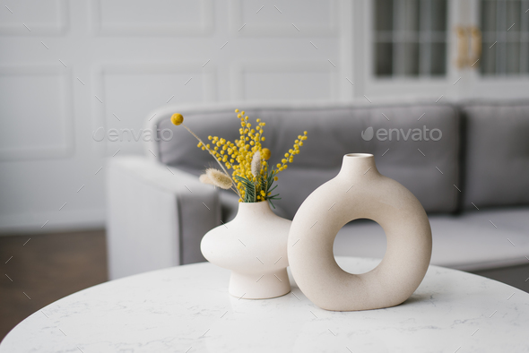Two decorative ceramic modern round vases with a hole inside on the table in the living room