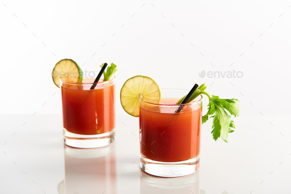 bloody mary cocktail in glasses garnished with lime and celery isolated on  white Stock Photo by LightFieldStudios