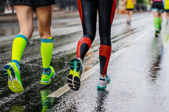 legs female runners running together marathon on wet asphalt