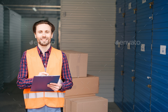 Waist-up of young man in work clothes into warehouse with self storage unit