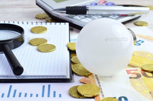 Magnifying glass on a pile of money coins. Stock Photo