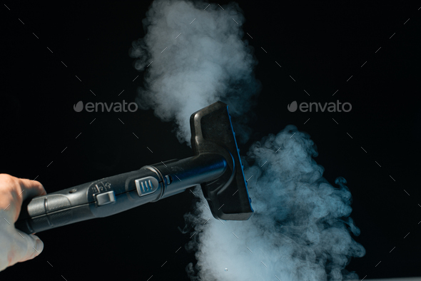 Steam clean brush in hand on black background. Clean concept