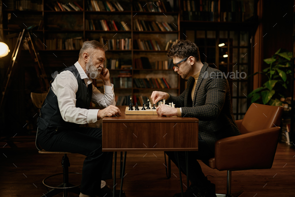 Side view on senior man and young guy chess player having friendly match at home