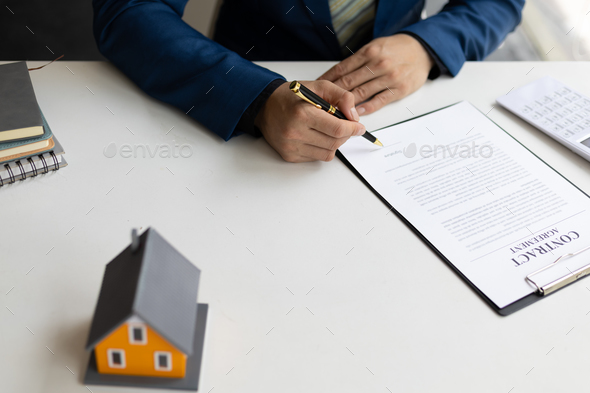 Businessman or real estate agent signs a contract to sell the house legally.