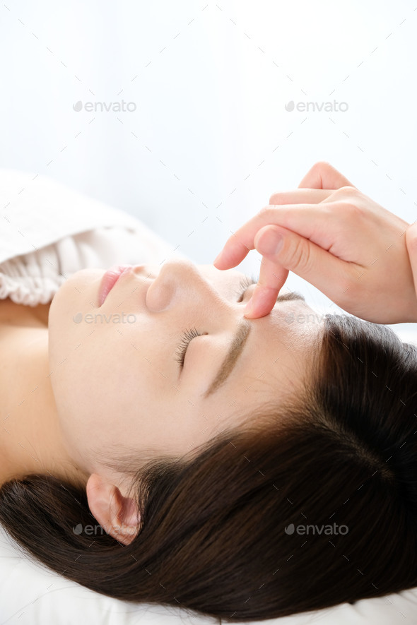 Woman receiving acupressure between the eyes at an acupuncture clinic