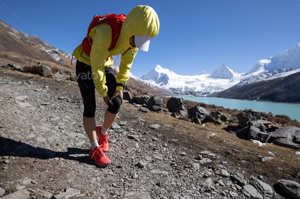 Woman runner with sports injured knee running at high altitude mountain trail - Stock Photo - Images