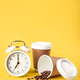 Alarm clock, paper cup and coffee beans on a yellow background isolated. - PhotoDune Item for Sale