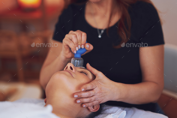 Woman having a face cupping massage in salon - Stock Photo - Images
