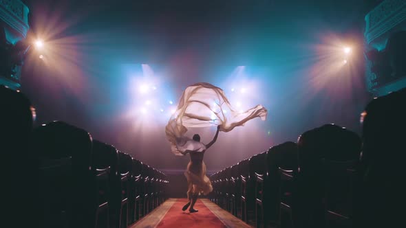 The muse of art. A young girl runs through the theater with a huge silk fabric. Ballet
