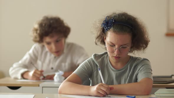 Pupils at School. The Boy Tugs at the Girls Hair, the Girl Hit Him on the Head with a Book. Bullying alt