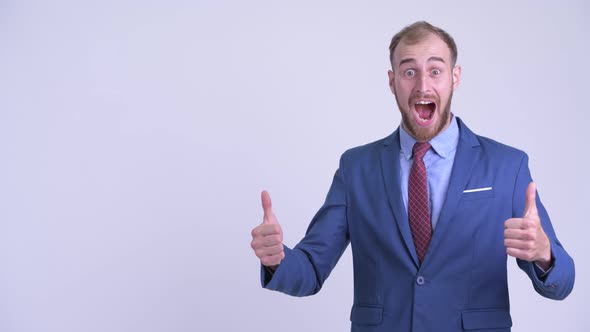 Happy Bearded Businessman Pointing To the Side and Looking Surprised