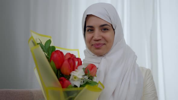 Closeup Portrait of Confident Charming Woman in White Hijab Smelling Wedding Bouquet Looking at alt