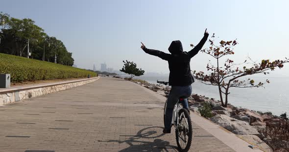 Woman riding bike hands free cycling with arms outstretched in the sunny coast alt