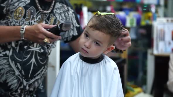 Children's Haircut in the Salon at the Time of the Coronavirus Epidemic. Little Boy Gets a Haircut alt