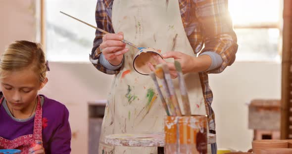 Mother and daughter painting a bowl alt