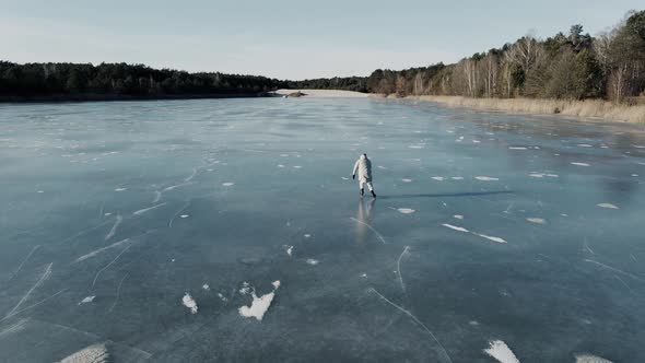 Shot of Man Skating on a Frozen Lake on a Sunny Winter Day Taken on a Drone