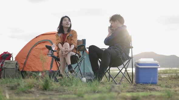 Young couple campers trekking in mountains park using film camera taking a photo.