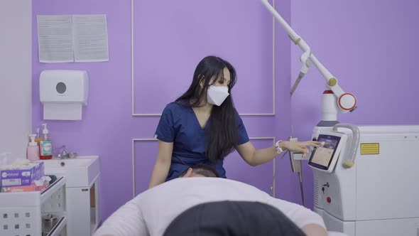 Cosmetologist Adjusting Laser Machine for Beauty Procedure in Thai Salon alt