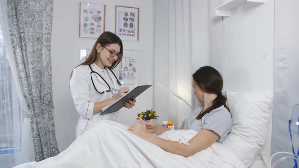Doctor in Hospital Room Talking with a Woman Patient and Assigns the Pills