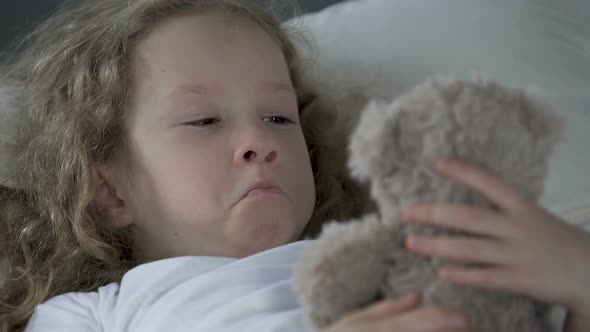 Orphan Girl Crying, Looking at Her Teddy Bear and Dreaming About Family alt