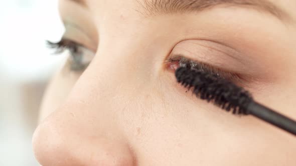 Close Up of Young Female Applying Mascara on Her Eyelashes alt
