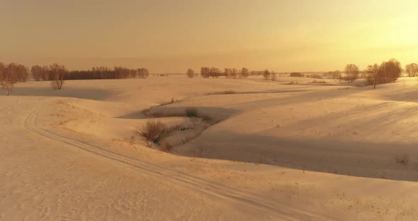 Aerial View of Cold Arctic Field Landscape Trees with Frost Snow Ice River and Sun Rays Over Horizon alt