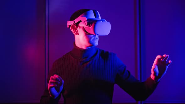 Man in a Virtual Reality Helmet Illuminated in Red and Blue Plays
