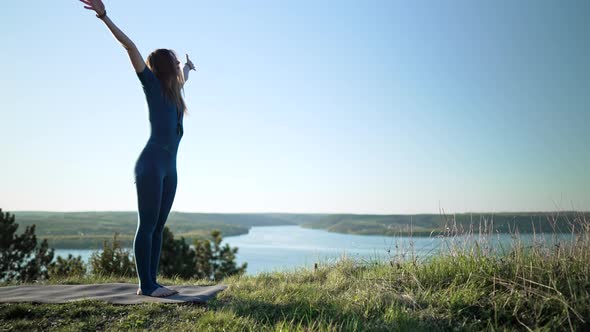 Yogi Woman Beginning Yoga Practice with Deep Breathing on Open Site of High Mountain alt