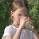 Happy Child Girl Drinking Milk From Glass Outdoors on Green Background in Summer - VideoHive Item for Sale