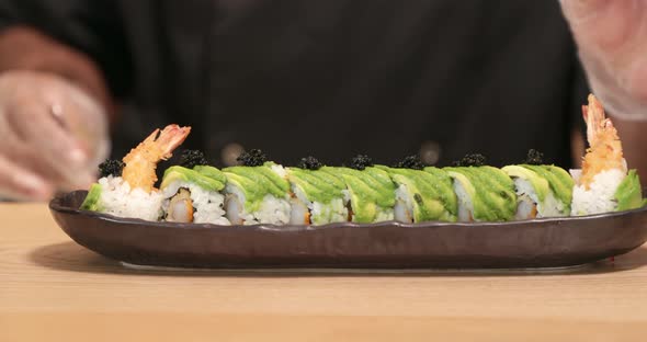 Chef Putting Black Caviar (roe) On Top Of Avocado On The Sushi Rolls. - close up shot alt